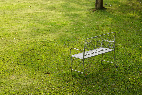 Vintage white metal garden chair on an empty green lawn in a peaceful backyard garden