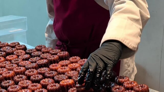Cooks prepare and display freshly baked canel&eacute;s at local bakery in early morning hours. Traditional french dessert.
