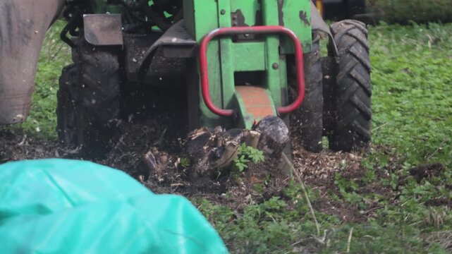 A stump grinder grinds down a tree stump in the soil.