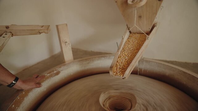 Cinematic Close-up of Dried Corn Kernels Flowing into a Traditional Rotating Stone Mill, Flores Island, Azores