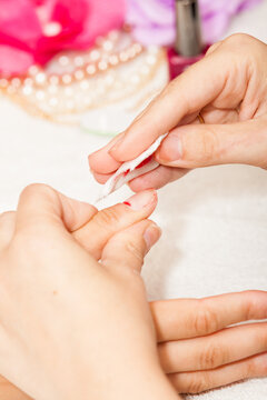 The esthetician removes the old nail polish with a cotton and remover