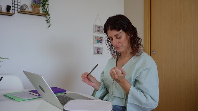 Woman filing nails while procrastinating at her home office desk