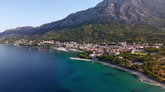 Aerial view of the coastal town of Baska Voda on the Makarska Riviera in Croatia, featuring the Biokovo mountain range and the crystal clear Adriatic Sea
