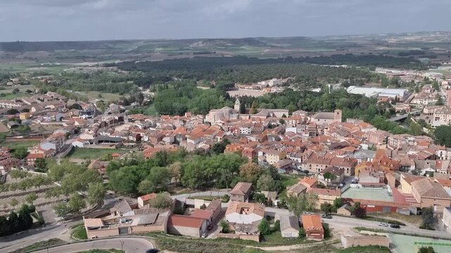 Aerial view of Pe&ntilde;afiel, Spain, featuring its dense urban landscape with terracotta roofs, historic church towers, and modern architecture integrated into the traditional Castilian town center.