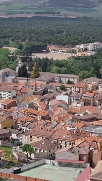 Aerial view of Pe&ntilde;afiel, Spain, featuring its dense urban landscape with terracotta roofs, historic church towers, and modern architecture integrated into the traditional Castilian town center.