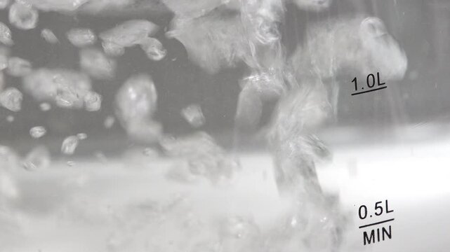 4K water boiling furiously with large bubbles inside glass electric kettle showing 1.0L and 0.5L MIN level indicators.