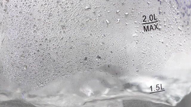 4K water droplets and condensation on transparent glass electric kettle showing 2.0L MAX and 1.5L water level indicators. 