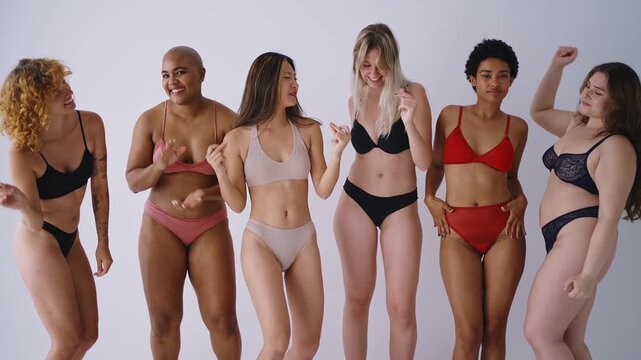 Multiethnic group of women wearing underwear with diverse kind of bodies. Young women having fun in a studio , posing in lingerie and feeling good in their body.
