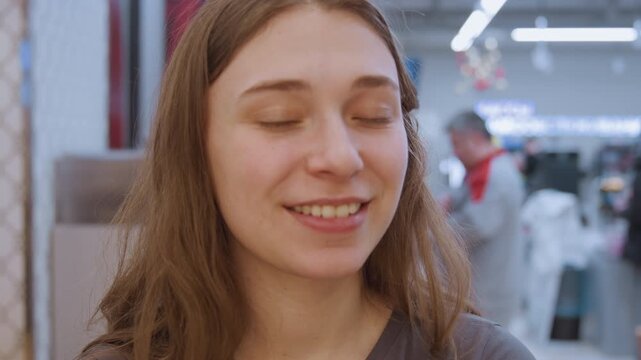 Youthful skincare demonstration. Young woman playfully testing beauty product in retail environment. Female consumer joyfully examines skincare sample with makeup and packaging details visible
