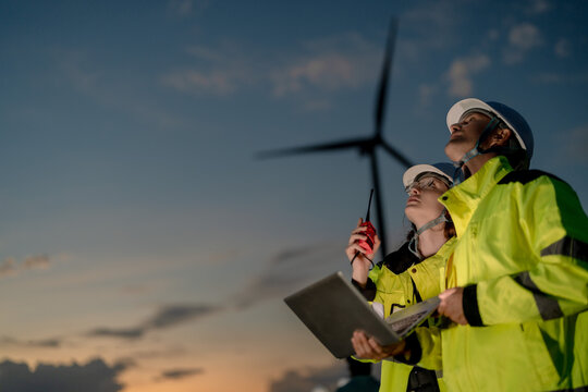Delivering clean power. Dedicated engineers coordinating onshore wind farm operations at dusk. Building a reliable and sustainable tomorrow.