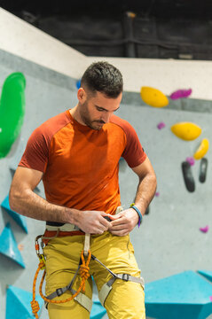 Male climber preparing safety harness for indoor bouldering