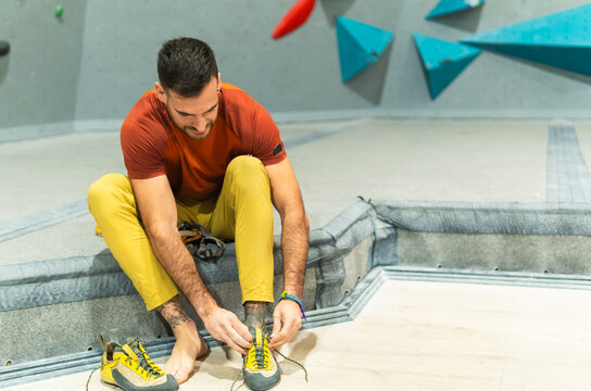 Man making off his climbing shoes after practicing for indoor bouldering