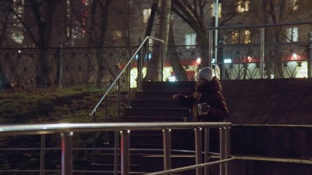 Energetic busker on park staircase arms raised in expressive gesture, spotlighted by city lights, metal rail foreground, evening mood with hints of crowd, triumphant rhythm and cinematic motion