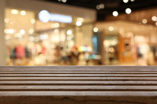 Empty wood table top with blur clothing boutique display interior shopping mall background