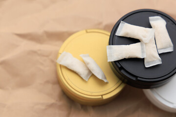 Obraz premium Different colored containers hold snus pouches with nicotine pads placed on a brown background