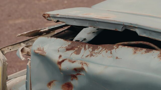 Rusty abandoned car in a deserted area. Damaged vehicle left to decay, showing signs of age and weathering. Evokes feelings of neglect, decay, and forgotten history.