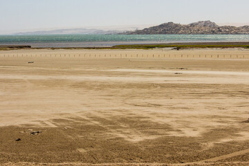 Fototapeta premium View over a saltflat with the Atlantic ocean in the background on the Luderitz Penninsula in the Tsau ǁKhaeb National Park, in Namibia.
