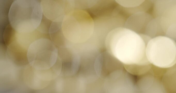 Beautiful warm golden and yellow abstract bokeh background slowly shimmering and sparkling. A soft, out-of-focus, glittering, and unfocused backdrop for festive and celebratory occasions