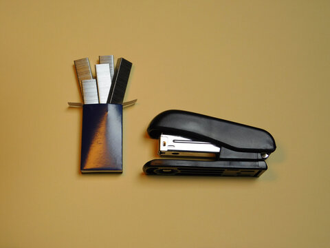 Black Stapler and Open Box of Staples on Minimal Beige Background