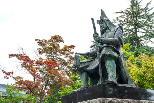 米沢市 上杉神社の境内に佇む「上杉謙信公之像」、威厳ある武将の坐像と色付き始めた秋の木々/Stately Bronze Statue of Lord Uesugi Kenshin at Uesugi Shrine with Trees Beginning to Color for Autumn