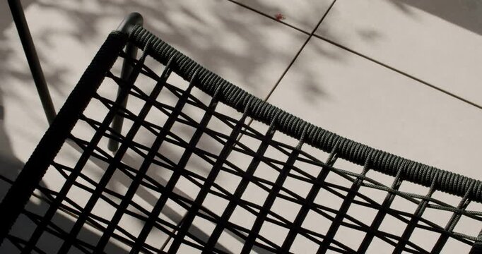 Close-up of a woven, dark-colored chair. The woven pattern creates a grid-like design, adding a touch of modern style and comfort.