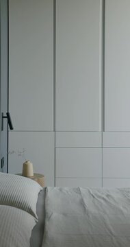 Modern Bedroom Interior Design With White Wardrobe and Wall Decor. Minimalist Style Bedroom With Neutral Color Palette and Elegant Furniture. Pillows and Blanket on the Bed. Stylish and Comfortable