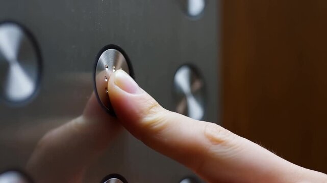 Slow motion handheld close up of finger pressing elevator button on stainless steel panel inside building elevator cabin during daytime routine