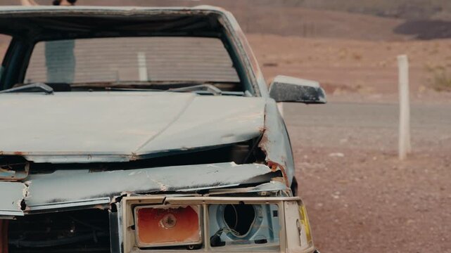 Abandoned car wreck on the side of a highway. The car appears old, damaged, and rusty. It evokes feelings of decay and loneliness, hinting at a past incident or story.