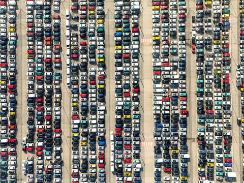Aerial view of thousands of colorful new cars parked in neat vertical rows at a large automotive logistics hub in Rivalta di Torino, Piedmont, Italy.