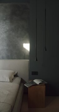 Modern bedroom interior design with dark gray walls, minimalist furniture, and ambient lighting. A wooden nightstand holds an open book, creating a cozy atmosphere.
