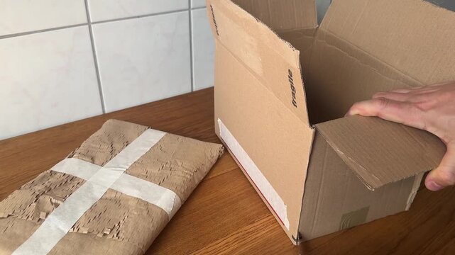 Hands cutting cardboard to prepare a custom shipping box. Ecommerce packaging and parcel preparation concept.