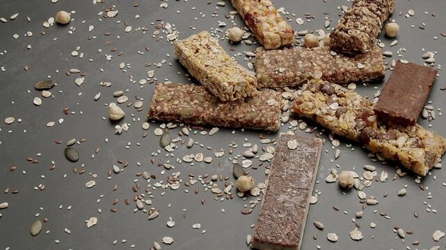 A variety of granola bars with nuts and seeds scattered on a dark background. Perfect for healthy snacking and nutrition concepts. Variety of Healthy Granola Bars with Oats and Nuts