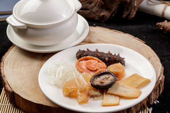 The white porcelain tableware on the pine cutting board clattered against the rich seafood soup.