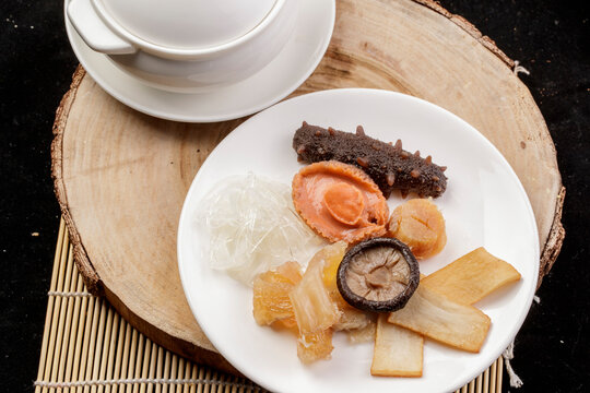 The white porcelain tableware on the pine cutting board clattered against the rich seafood soup.