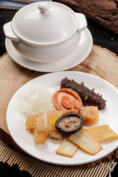 The white porcelain tableware on the pine cutting board clattered against the rich seafood soup.