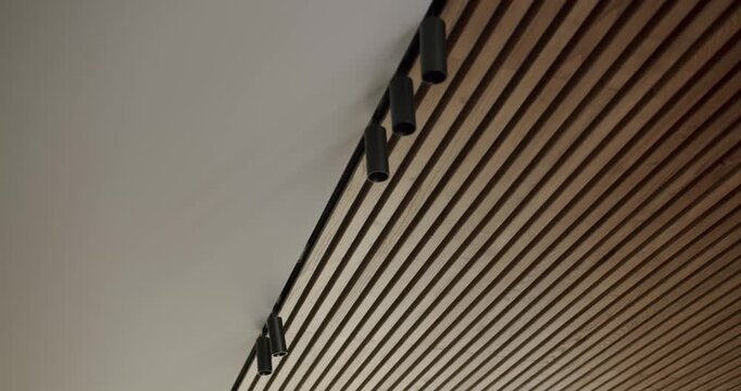 Wooden planks on a ceiling, creating an interesting perspective. The parallel lines and warm tones of the wood add a touch of modern design. Ideal for backgrounds, architecture, or design projects.