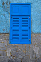 Fototapeta premium Blue wooden shuttered window on rustic textured wall