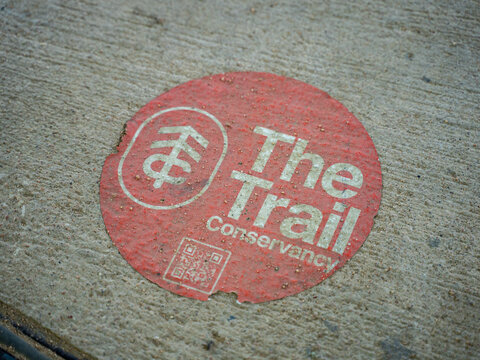 Red Sticker For The Trail Conservancy With QR Code on Concrete Pavement in Austin, Texas