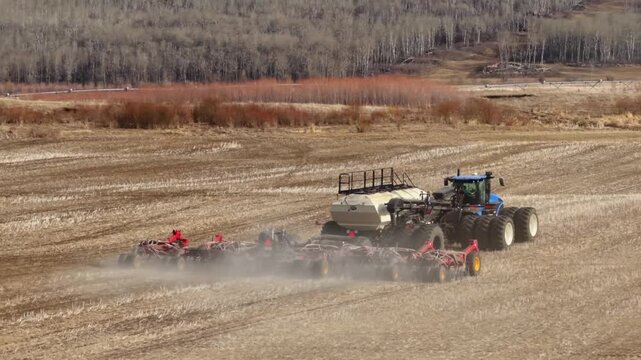 Large Tractor Pulling Air Seeder Through Cultivated Field