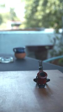 Primer plano vertical de pipa de madera cl&aacute;sica sobre mesa de madera con fondo desenfocado y luz natural de d&iacute;a.