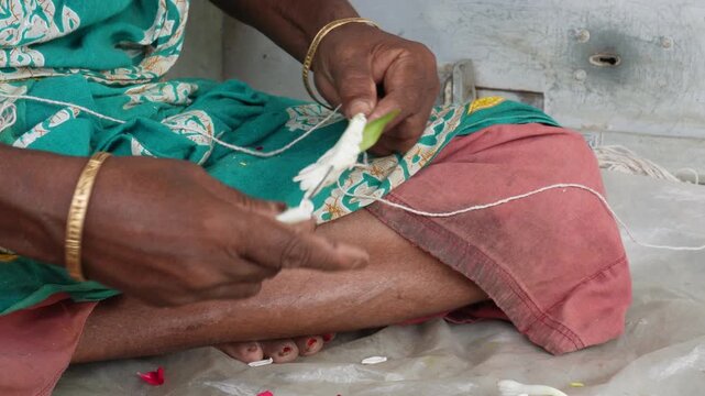 Skilled hands creating fragrant tuberose flower gajra