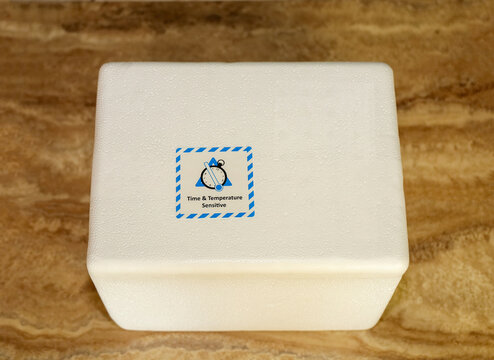 Insulated Styrofoam Shipping Container with Time and Temperature Sensitive Warning Label. A white polystyrene foam cooler used for transporting perishable goods.