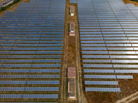 Aerial view of a large solar panel farm with rows of photovoltaic modules and utility buildings in Manacor, Balearic Islands, Spain.