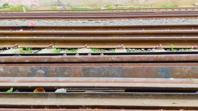 Close up shot of industrial rusty steel railway tracks and gravel on a sunny day with perspective view of the line