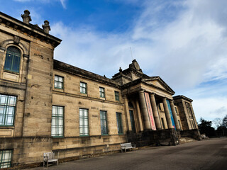 Obraz premium Historic neoclassical Modern Two Dean Gallery building with columns and stone facade in Edinburgh, Scotland, UK, with couple sitting on a bench under a cloudy sky