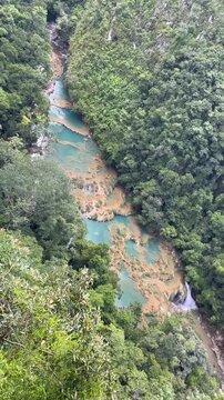 Scenic aerial style view of turquoise river pools and small waterfalls surrounded by dense tropical rainforest in Semuc Champey, Guatemala.