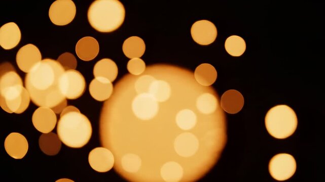 Illuminating golden orbs gently float across a dark, velvety canvas, creating a mesmerizing, ethereal glow that evokes feelings of wonder and festive celebration