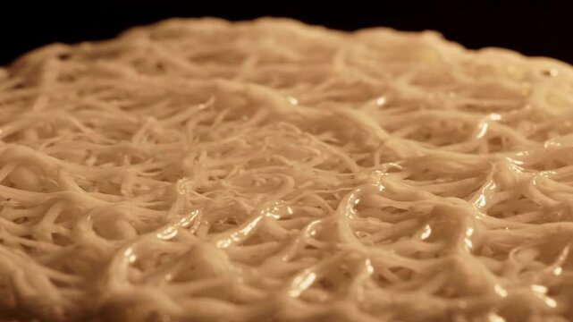 Closeup macro shot of fine white noodles being drizzled with liquid, abstract texture with organic pattern