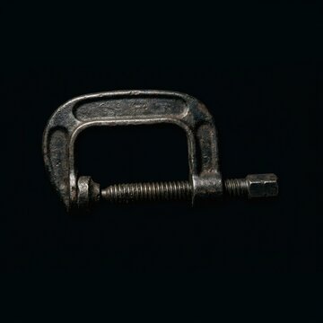 Old metal C clamp on black background