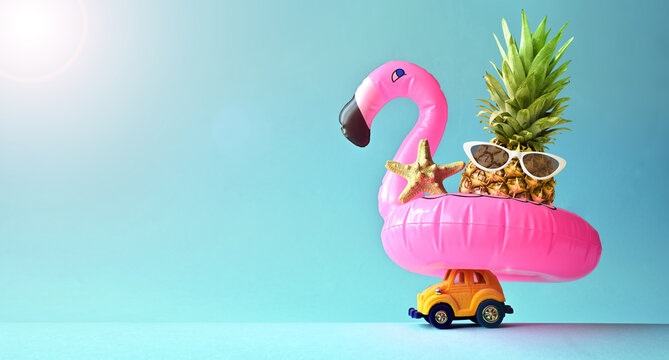 Pink inflatable flamingo on toy car and pineapple. Summer pool float party idea. Summer concept.
